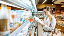 Una consumidora elige leche vegetal en un supermercado.