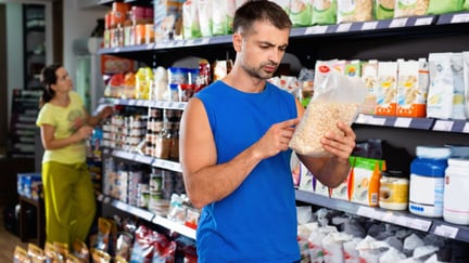 Una persona mira etiquetas de suplementos en una tienda. Consumo consciente con los animales.